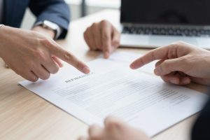 Mãos apontando para cláusulas importantes em contrato de refinanciamento
