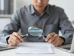 Pessoa lendo atentamente contrato de refinanciamento de veículo com lupa